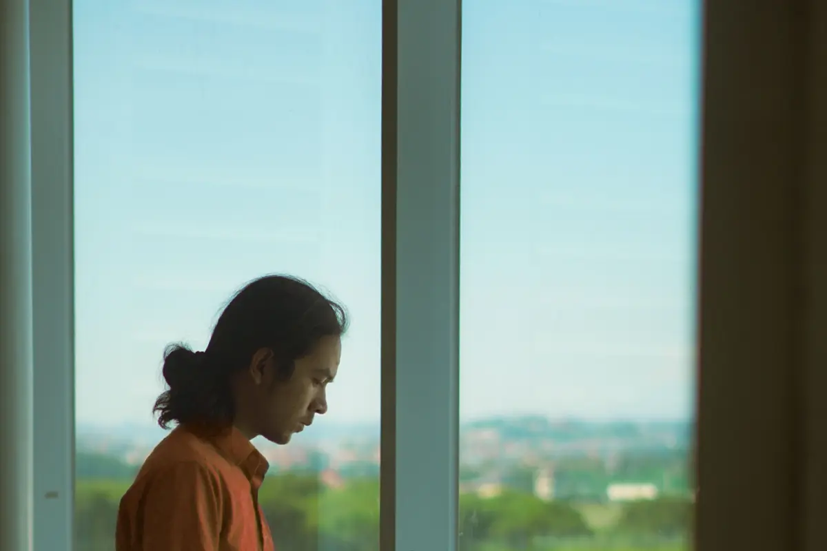 Traveller checking a phone by a large airport window overlooking the apron