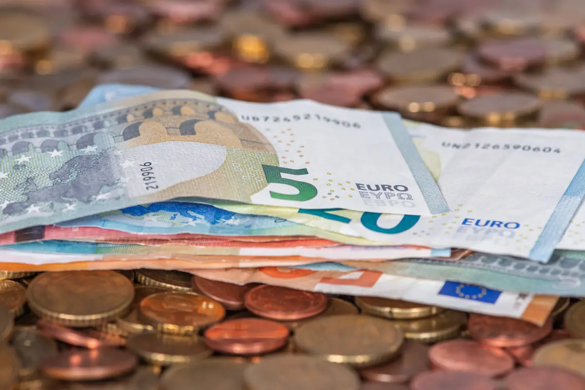 Euro banknotes fanned out on a heap of euro coins