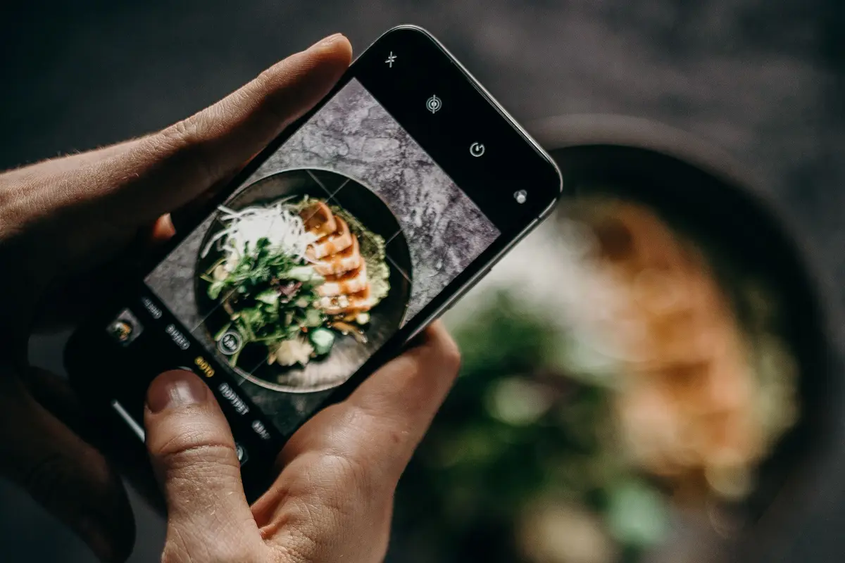 Hands photographing a bowl of food from above with a smartphone